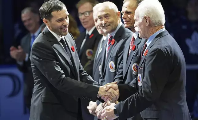 2024 Hockey Hall of Fame inductee Pavel Datsyuk, left, shakes hands with Lanny McDonald, right, during a ceremony prior to NHL hockey game action between the Detroit Red Wings and the Toronto Maple Leafs in Toronto, Friday, Nov. 8, 2024. (Frank Gunn/The Canadian Press via AP)