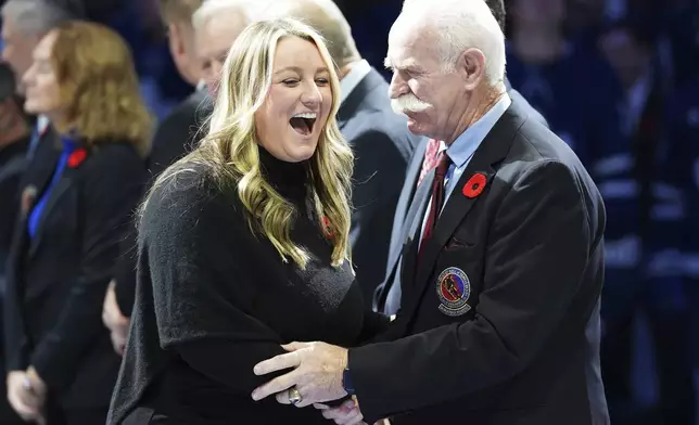 2024 Hockey Hall of Fame inductee Krissy Wendell-Pohl, left, shakes hands with Lanny McDonald, right, during a ceremony prior to NHL hockey game action between the Detroit Red Wings and the Toronto Maple Leafs in Toronto, Friday, Nov. 8, 2024. (Frank Gunn/The Canadian Press via AP)