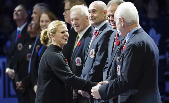 2024 Hockey Hall of Fame inductee Natalie Darwitz, left, shakes hands with Lanny McDonald, right, during a ceremony prior to NHL hockey game action between the Detroit Red Wings and the Toronto Maple Leafs in Toronto, Friday, Nov. 8, 2024. (Frank Gunn/The Canadian Press via AP)