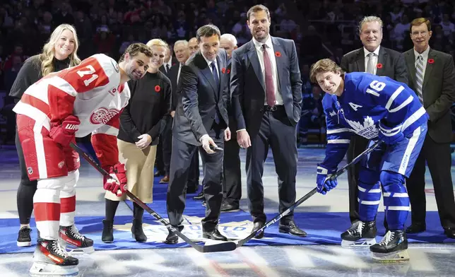 2024 Hockey Hall of Fame inductees Krissy Wendell-Pohl, from back left to right, Natalie Darwitz, Pavel Datsyuk, Shea Weber, Jeremy Roenick and David Poile pose for a ceremonial face off photo with Detroit Red Wings' Dylan Larkin (71) and Toronto Maple Leafs' Mitch Marner (16) during a ceremony prior to NHL hockey game action in Toronto, Friday, Nov. 8, 2024. (Frank Gunn/The Canadian Press via AP)