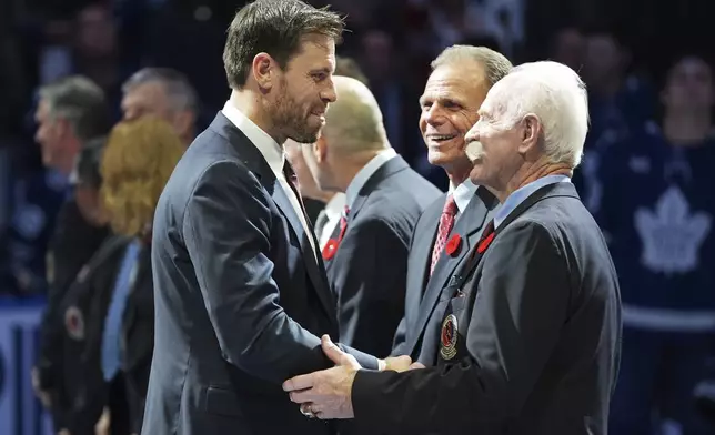 2024 Hockey Hall of Fame inductee Shea Weber, left, shakes hands with Lanny McDonald, right, as Mike Gartner, center, looks on during a ceremony prior to NHL hockey game action between the Detroit Red Wings and the Toronto Maple Leafs in Toronto, Friday, Nov. 8, 2024. (Frank Gunn/The Canadian Press via AP)