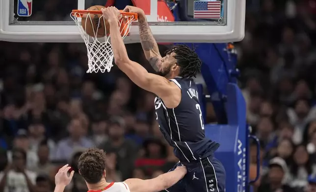 Dallas Mavericks center Dereck Lively II, top, dunks as Houston Rockets' Alperen Sengun, bottom, defends in the first half of an NBA basketball game in Dallas, Thursday, Oct. 31, 2024. (AP Photo/Tony Gutierrez)