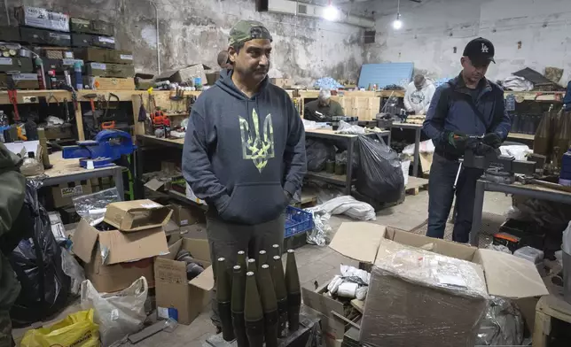 Amed Khan, a U.S. human rights advocate, political activist and philanthropist, center, stands inside a workshop of Ukraine's attack drones battalion "Achilles" in Kharkiv region, Ukraine, Sunday, Oct. 27, 2024. (AP Photo/Efrem Lukatsky)