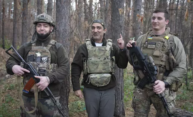 U.S. philanthropist Amed Khan, center, surrounded by Ukrainian servicemen reacts on the sounds of shelling on the frontline in Kharkiv region, Ukraine, Monday, Oct. 28, 2024. (AP Photo/Efrem Lukatsky)