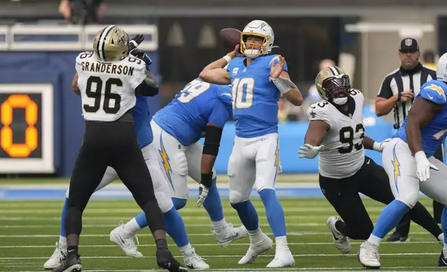 Los Angeles Chargers quarterback Justin Herbert (10) passes between New Orleans Saints defensive end Carl Granderson (96) and defensive tackle Nathan Shepherd (93) in the first half of an NFL football game in Inglewood, Calif., Sunday, Oct. 27, 2024. (AP Photo/Mark J. Terrill)