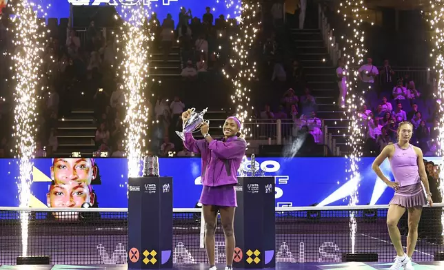 Coco Gauff of the U.S. holds her trophy next to China's Qinwen Zheng, after defeating her in their women's singles final match of the WTA finals at the King Saud University Indoor Arena, in Riyadh, Saudi Arabia, Saturday, Nov. 9, 2024. (AP Photo)