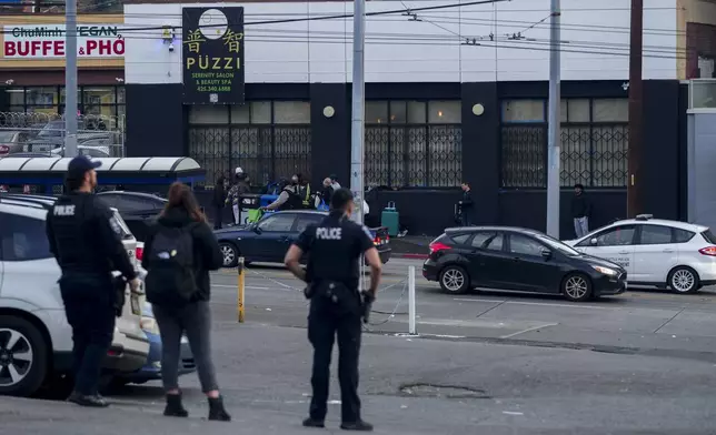 Police officers stand near the scene as they gather security camera footage after multiple people were stabbed Friday, Nov. 8, 2024, in the Chinatown-International District in Seattle. (AP Photo/Lindsey Wasson)