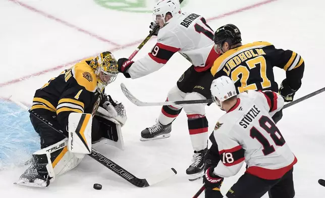 Boston Bruins' Jeremy Swayman (1) blocks a shot as Hampus Lindholm (27) defends agasint Ottawa Senators' Drake Batherson (19) and Tim Stützle (18) during the first period of an NHL hockey game, Saturday, Nov. 9, 2024, in Boston. (AP Photo/Michael Dwyer)