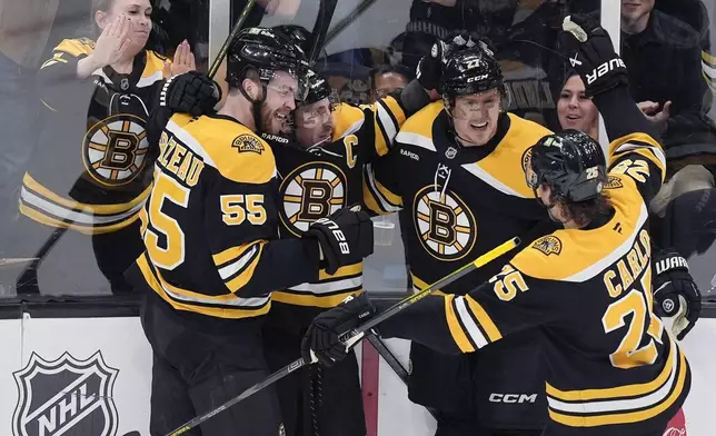 Boston Bruins' Brad Marchand (63) celbrates his goal with Justin Brazeau (55), Brandon Carlo (25) and Hampus Lindholm (27) during the second period of an NHL hockey game against the Ottawa Senators, Saturday, Nov. 9, 2024, in Boston. (AP Photo/Michael Dwyer)