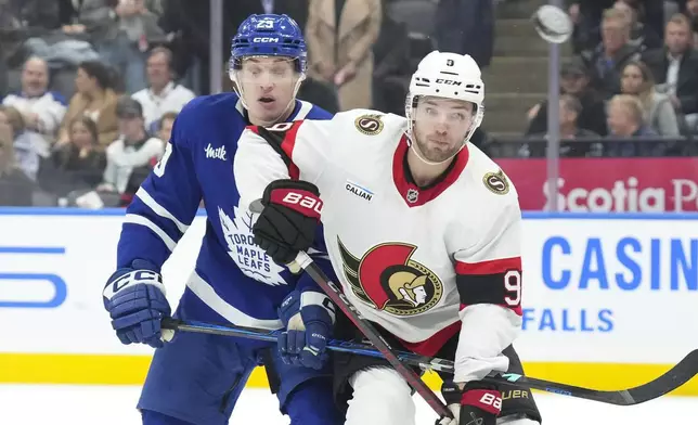 Ottawa Senators' Josh Norris, right, eyes the puck as he battles for position with Toronto Maple Leafs' Pontus Holmberg during the first period of an NHL hockey game in Toronto, Tuesday, Nov. 12, 2024. (Chris Young/The Canadian Press via AP)