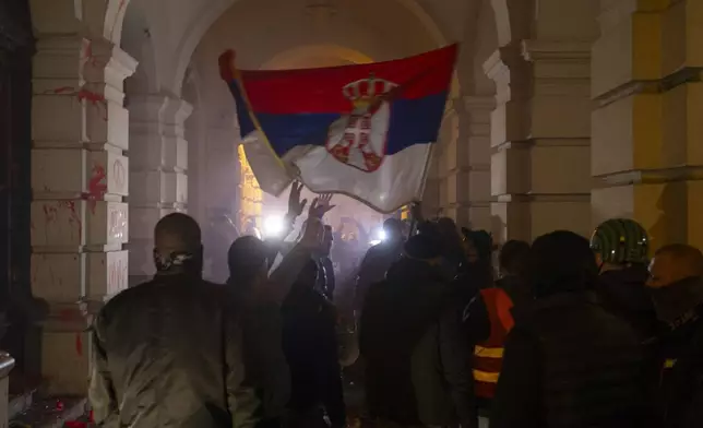 Protesters carry a Serbian flag outside the City Hall building, during a protest in rage over last week's collapse of a concrete canopy at the railway station that killed 14 people, in Novi Sad, Serbia, Tuesday, Nov. 5, 2024. (AP Photo/Marko Drobnjakovic)