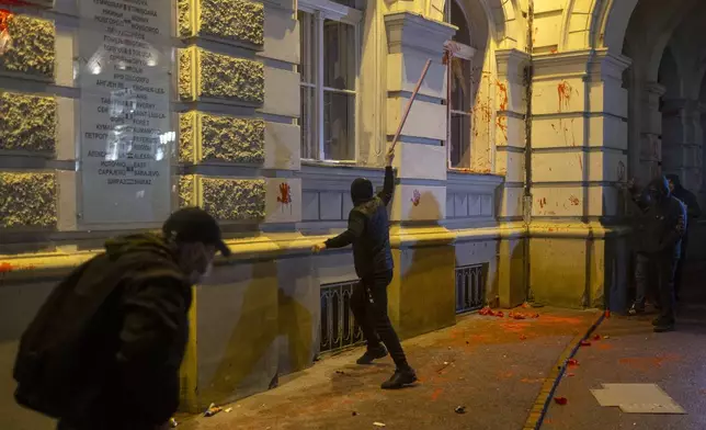 A rioter breaks a window on the City Hall building during a protest in Novi Sad, Serbia, Tuesday, Nov. 5, 2024. (AP Photo/Marko Drobnjakovic)