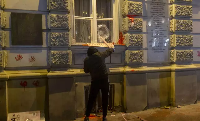 A protester crashes the window on the City Hall building during a protest in rage over last week's collapse of a concrete canopy at the railway station that killed 14 people in Novi Sad, Serbia, Tuesday, Nov. 5, 2024. (AP Photo/Marko Drobnjakovic)