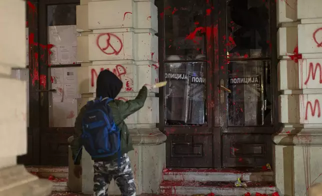 A protester points at riot police as they cover inside the City Hall building during a protest in rage over last week's collapse of a concrete canopy at the railway station that killed 14 people, in Novi Sad, Serbia, Tuesday, Nov. 5, 2024. (AP Photo/Marko Drobnjakovic)