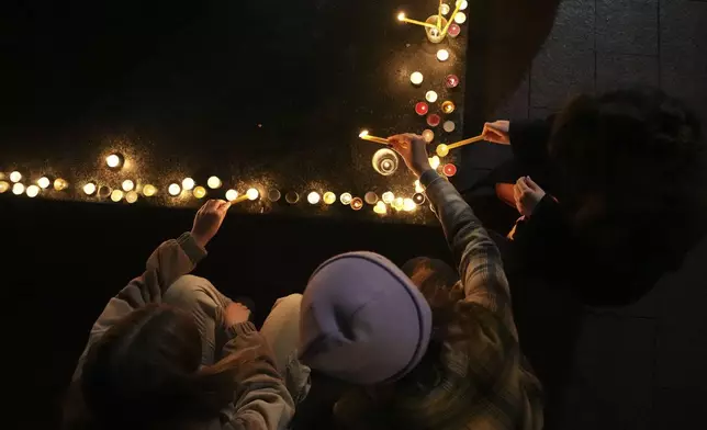 People light candles for the victims after an outdoor roof collapsed at a train station in Novi Sad, Serbia, Friday, Nov. 1, 2024. (AP Photo/Darko Vojinovic)