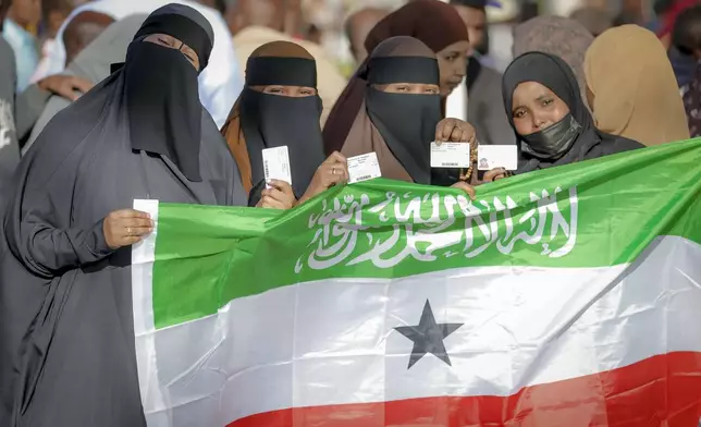 People display the Somaliland flag as they wait to cast their vote during the 2024 Somaliland presidential election at a polling station in Hargeisa, Somaliland, Wednesday, Nov. 13,2024. (AP Photo/Abdirahman Aleeli)