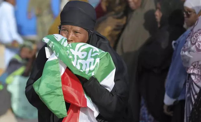 A woman kiss the Somaliland flag as she waits to cast her vote during the 2024 Somaliland presidential election at a polling station in Hargeisa, Somaliland, Wednesday, Nov. 13,2024. (AP Photo/Abdirahman Aleeli)