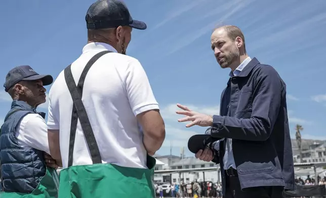 Britain's Prince William, right, speaks to local fisherman in Kalk Bay Harbour, near Cape Town, South Africa Thursday, Nov. 7, 2024. (Gianluigi Guercia/Pool Photo via AP)