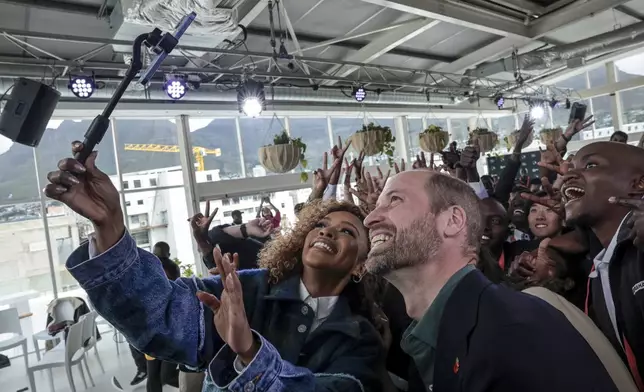 Nomzamo Mbatha, left, the host of Earthshot Week, takes a selfie with Britain's Prince William and a group of young people at the Earthshot Prize Climate Leaders Youth Programme at Rooftop on Bree in Cape Town, South Africa, Monday Nov. 4, 2024. (Gianluigi Guercia/Pool Photo via AP)