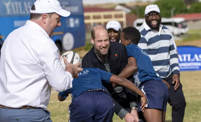 Britain's Prince William, is tackled playing rugby with pupils at the Ocean View Secondary School in Cape Town, South Africa, Monday, Nov. 4, 2024. (AP Photo/Jerome Delay-pool)