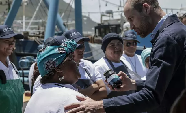 Britain's Prince William, the Prince of Wales receives a gift from a local, at Kalk Bay Harbour, near Cape Town, Thursday, Nov. 7, 2024. (Gianluigi Guercia/Pool Photo via AP)