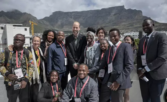 Britain's Prince William, center, poses for a photo with a group of young people, with Table Mountain in the background, at the Earthshot Prize Climate Leaders Youth Programme at Rooftop on Bree in Cape Town, South Africa, Monday Nov. 4, 2024. (Gianluigi Guercia/Pool Photo via AP)