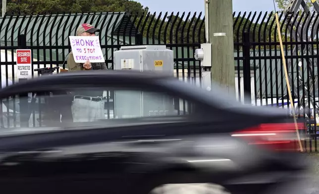 A protestor holds up a sign as traffic bypasses prior to the scheduled execution of Richard Moore, Friday, Nov. 1, 2024, outside of Broad River Correctional Institution in Columbia, S.C. (AP Photo/Matt Kelley)