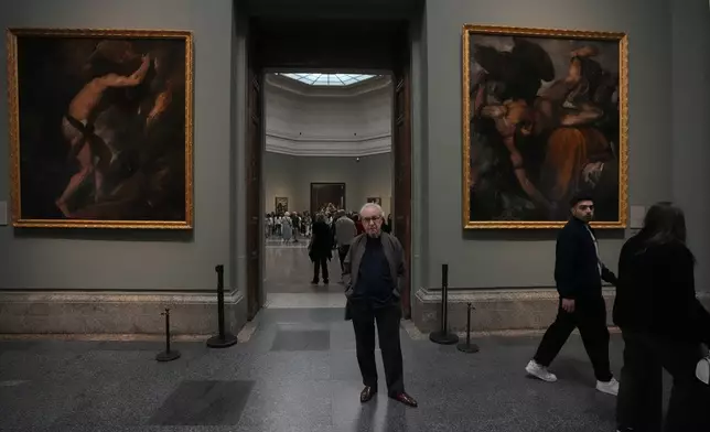 Novelist John Banville poses between Tiziano's 'Sisyphus' on left and Tityus on right at the Prado Museum in Madrid, Spain, Wednesday, Oct. 23, 2024. (AP Photo/Paul White)