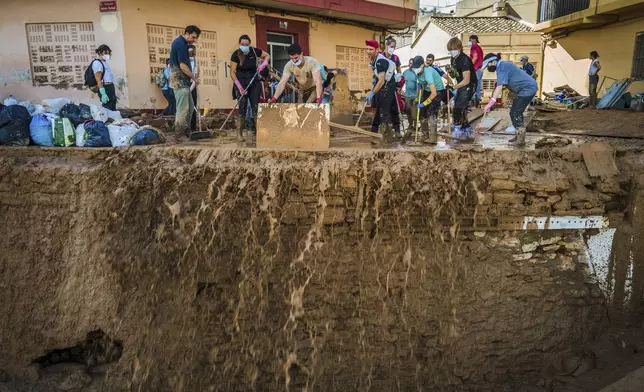 Volunteers and residents cleanup the mud four days after flash floods swept away everything in their path in Paiporta, outskirts of Valencia, Spain, Saturday, Nov. 2, 2024.(AP Photo/Angel Garcia)