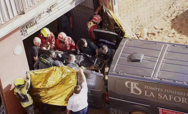 Members of the Spanish Guardia Civil carry the body of a person who died during floods in Valencia, Spain, Thursday, Oct. 31, 2024. (AP Photo/Alberto Saiz)