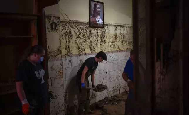 A painting hangs near the water level marker as resident remove the mud in a house after floods in Paiporta, Valencia, Spain, Tuesday, Nov. 5, 2024. (AP Photo/Emilio Morenatti)