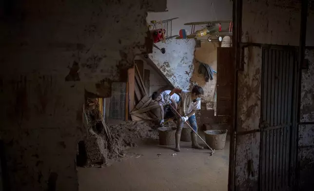 Volunteers clean the mud of Vero Almarche's house badly affected by flooding in Masanasa, Valencia, Spain, Wednesday, Nov. 6, 2024. (AP Photo/Emilio Morenatti)