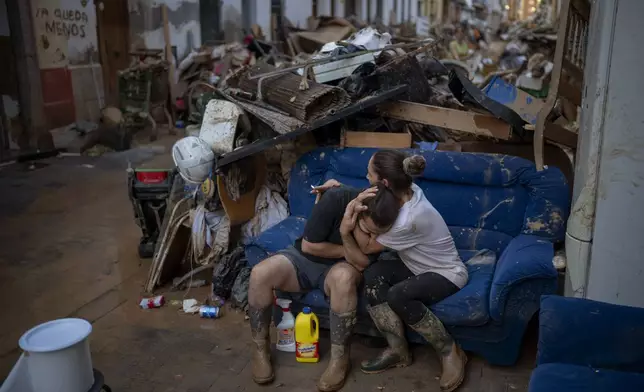 Tania hugs her brother-in-law Baruc after rescuing some of their belongings from their flooded house after the floods in Paiporta, Valencia, Spain, Tuesday, Nov. 5, 2024. (AP Photo/Emilio Morenatti)