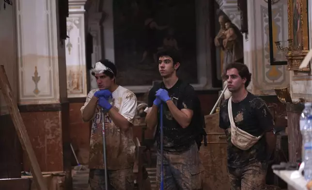 People who have been working in the clean-up attend a mass at the San Jorge church after floods in Paiporta, Spain, Thursday, Nov. 7, 2024. (AP Photo/Alberto Saiz)