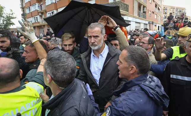 Spain's King Felipe VI is protected after a crowd of angry survivors of Spain's floods have tossed mud and shouted insults at the King and government officials when they made their first visit to one of the hardest hit towns after floods in Paiporta near Valencia, Spain, Sunday, Nov. 3, 2024. (AP Photo/Hugo Torres)