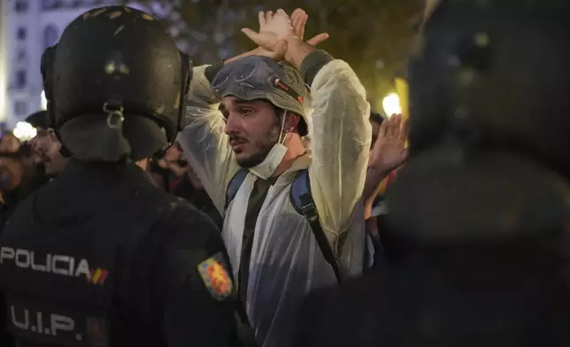 A demonstrator holds his hands up in front of riot police during a protest organized by social and civic groups, denouncing the handling of recent flooding under the slogan "Mazón, Resign," aimed at the president of the regional government Carlos Mazon, in Valencia, Spain, Saturday, Nov. 9, 2024. (AP Photo/Emilio Morenatti)