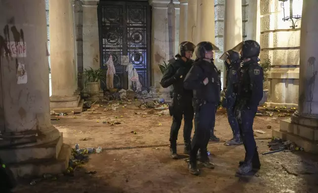 Riot police stand next to a government building littered by some demonstrators during minor clashes after a peaceful protest organized by social and civic groups, denouncing the handling of recent flooding under the slogan "Mazon, Resign," aimed at the president of the regional government Carlos Mazon, in Valencia, Spain, Saturday, Nov. 9, 2024. (AP Photo/Emilio Morenatti)