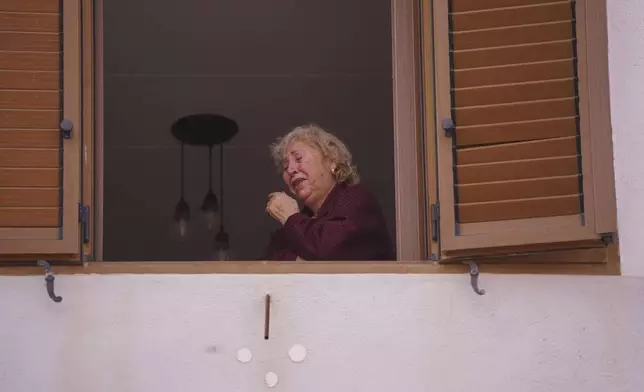 A woman cries by a window after floods in Paiporta, near Valencia, Spain, Monday, Nov. 4, 2024. (AP Photo/Alberto Saiz)