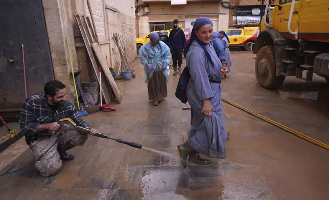 A nun gets her boots spray cleaned after floods in Paiporta, Spain, Thursday, Nov. 7, 2024. (AP Photo/Alberto Saiz)