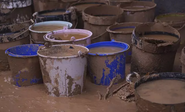 Buckets of collected mud and water sit in the street after floods on the outskirts of Valencia, Spain, Monday, Nov. 4, 2024. (AP Photo/Alberto Saiz)