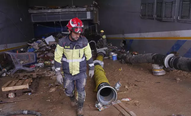 A firefighter works in the entrance of an underground car park in the MN4 shopping centre as rescue workers look for bodies on the outskirts of Valencia, Spain, Monday, Nov. 4, 2024. (AP Photo/Alberto Saiz)