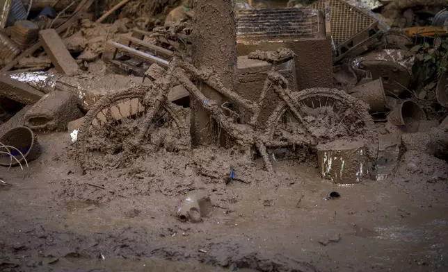 A bicycle is photographed covered in mud after the floods in Masanasa, Valencia, Spain, Thursday, Nov. 7, 2024. (AP Photo/Emilio Morenatti)