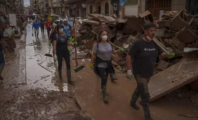 People walk through an area affected by floods, in Algemesi, Spain, Sunday, Nov. 3, 2024. (AP Photo/Manu Fernandez)