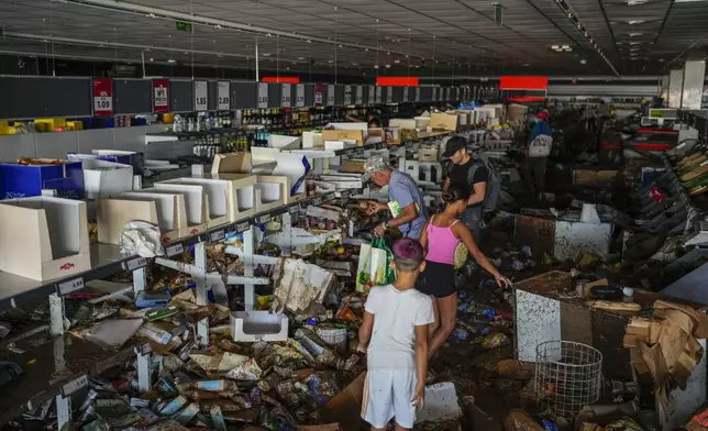 People pick up goods in a supermarket affected by the floods in Valencia, Spain, Thursday, Oct. 31, 2024. (AP Photo/Manu Fernandez)