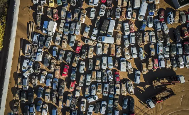 Cars sit on a plot used to store damaged vehicles four days after flash floods swept away everything in their path in the town of Benetússer, outskirts of Valencia, Spain, Saturday, Nov. 2, 2024.(AP Photo/Angel Garcia)