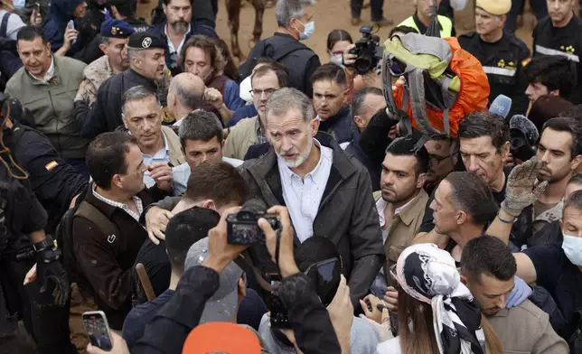 Spain's King Felipe VI, centre, speaks with protesters in Paiporta, near valencia, Spain, A crowd of angry survivors of Spain's floods have tossed mud and shouted insults at Spain's King Felipe VI and government officials when they made their first visit to one of the hardest hit towns. (Biel Alino/EFE via AP)