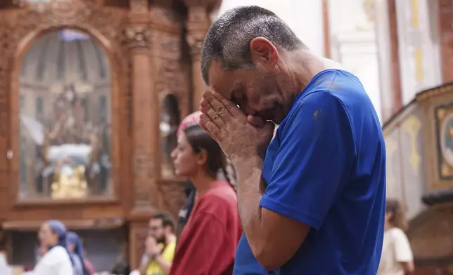 A man prays during a mass at the San Jorge church after floods in Paiporta, Spain, Thursday, Nov. 7, 2024. (AP Photo/Alberto Saiz)