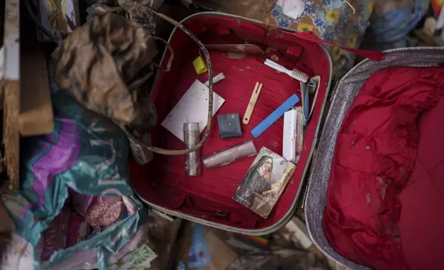 A religious image and various personal belongings covered by mud are pictured inside a suitcase, in Algemesi, Spain, Sunday, Nov. 3, 2024. (AP Photo/Manu Fernandez)