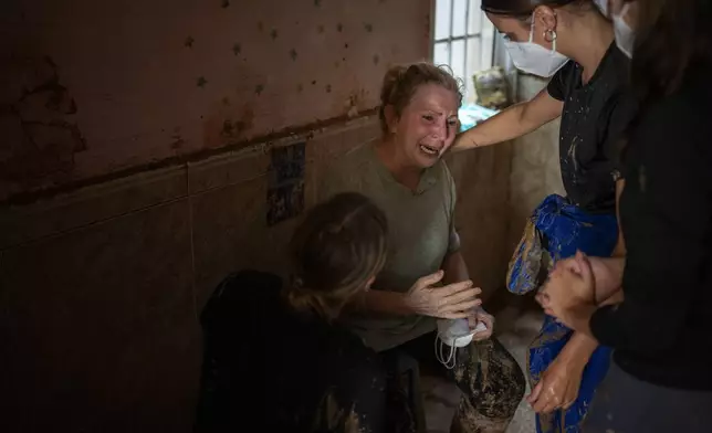 Dolores Merchan, 67, reacts as she is assisted by volunteers clearing mud from her home, where she has lived all her life with her husband and three children, and which has been severely affected by the floods, in Masanasa, Valencia, Spain, Thursday, Nov. 7, 2024. (AP Photo/Emilio Morenatti)