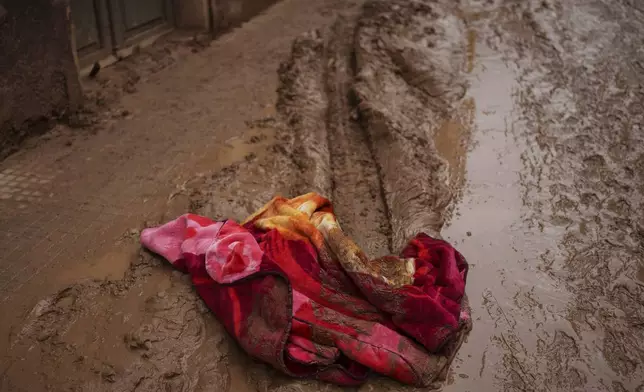 A blanket covered in mud is pictured in an area affected by floods, in Algemesi, Spain, Sunday, Nov. 3, 2024. (AP Photo/Manu Fernandez)